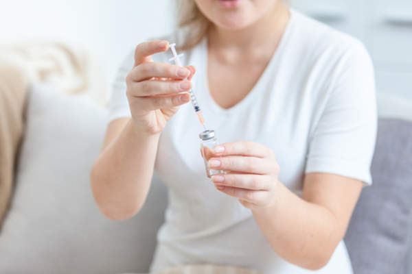 一名妇女在注射器里装满了生物药物,她准备给自己注射。