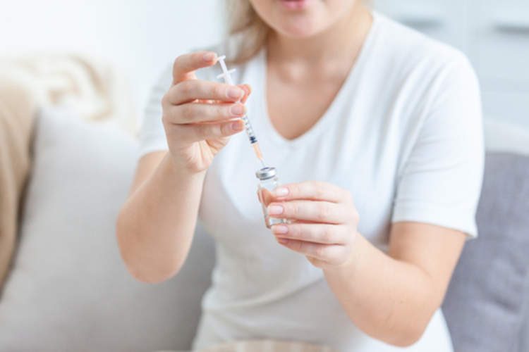 一名妇女在注射器里装满了生物药物,她准备给自己注射。