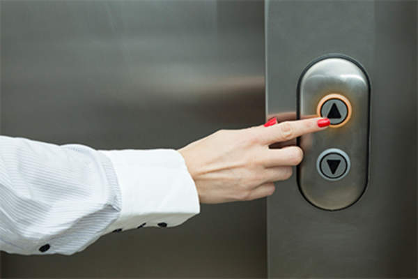 Woman pushing button on work place elevator.