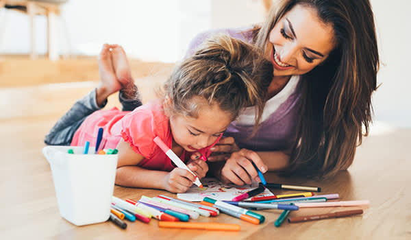 母亲和女儿用马克笔给一幅画着色。