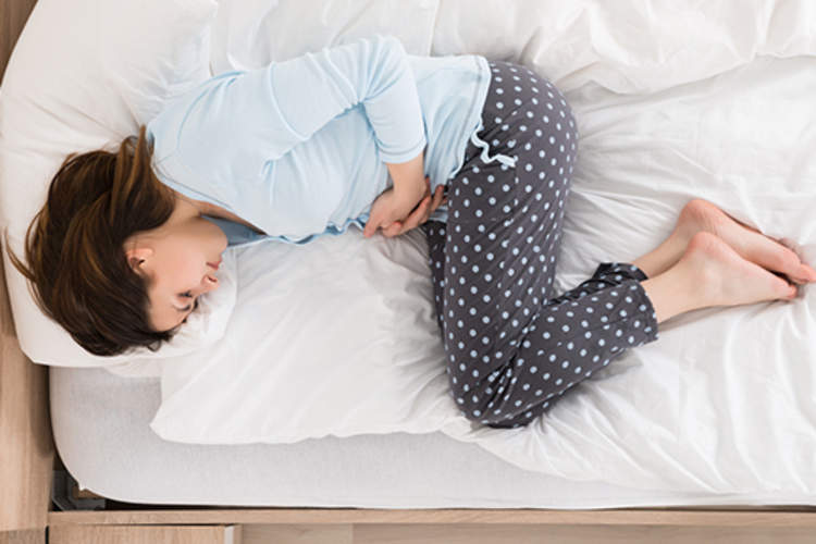 女人在床上痛苦地蜷缩。