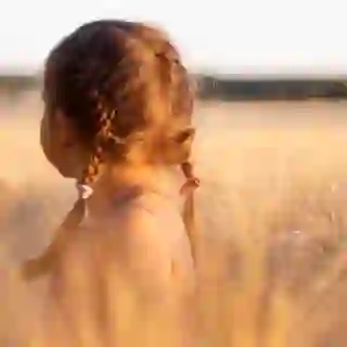 young girl in a wheat field looking away