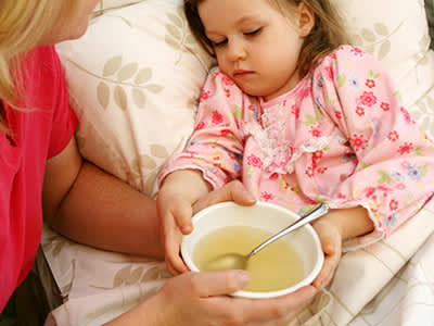妈妈给生病的小女孩喝汤。