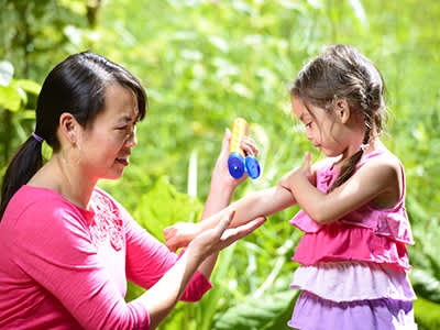 Woman putting sunscreen on young girl.