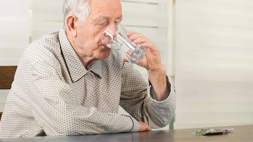 服用与杯水的老人用药。