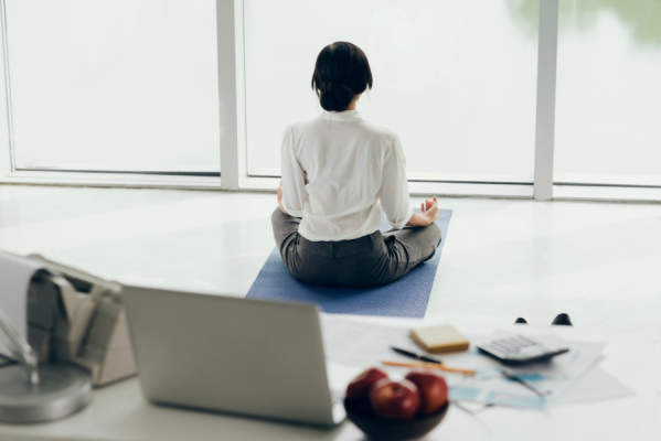 在办公室里坐在瑜伽垫上冥想的女人
