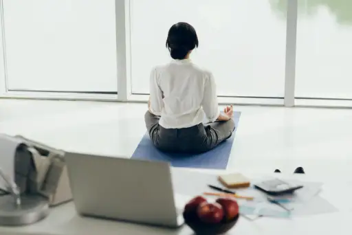 一位女士坐在办公室的瑜伽垫上冥想