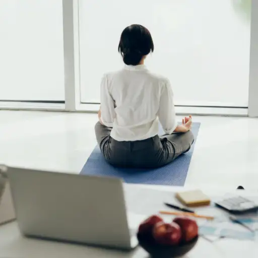 妇女坐瑜伽席子思考在办公室