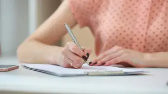 女人用钢笔在日记本上写字。