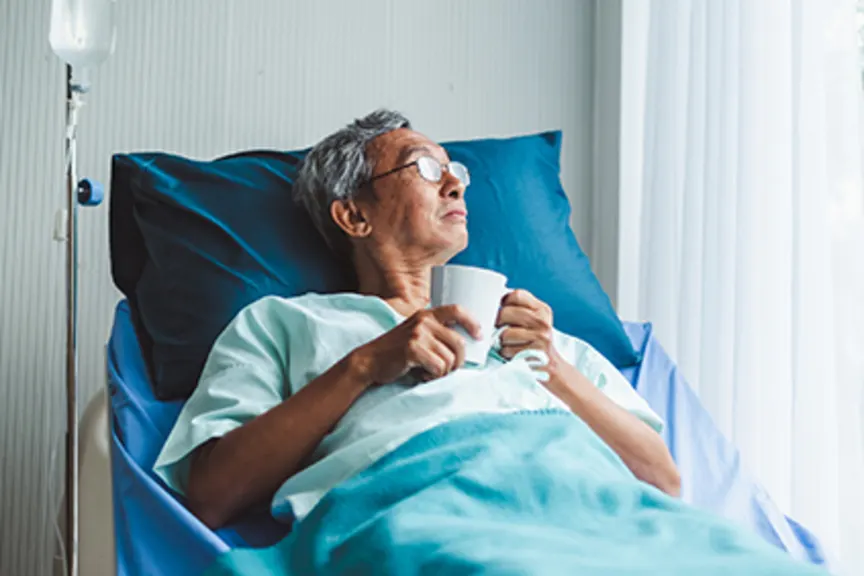 一个年长的男人躺在医院的病床上看着窗外。