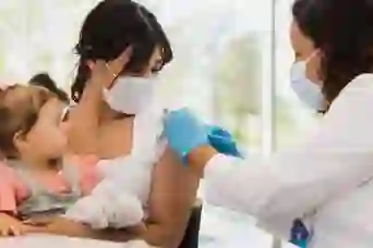 女婴看着她的妈妈注射疫苗