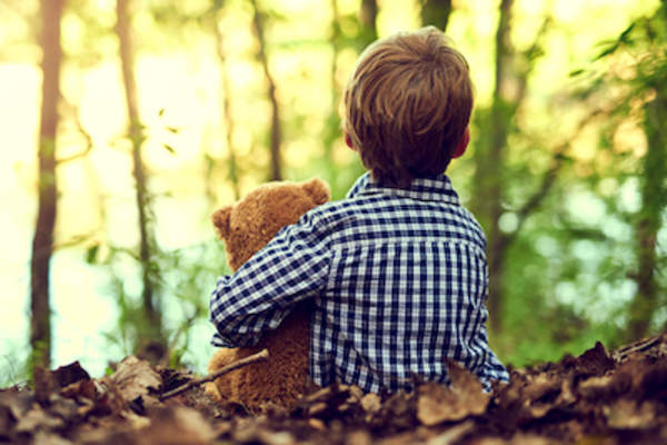 男孩和他的泰迪熊坐在一起。