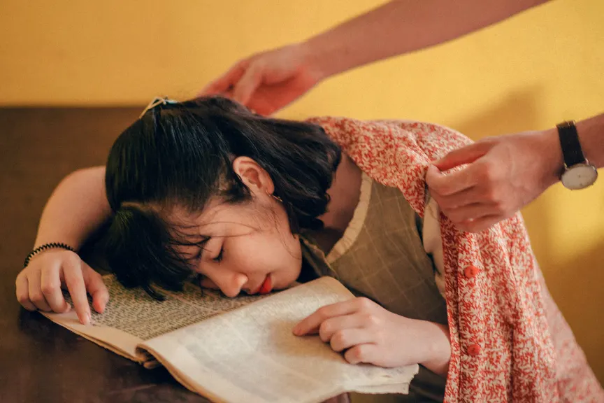 疲惫的年轻女子看书时睡着了。
