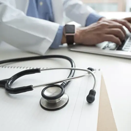 医生用笔记本电脑和听诊器打字。