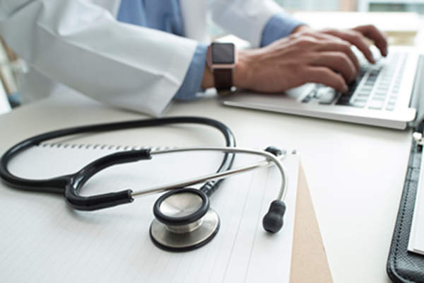 医生在笔记本电脑和听诊器上打字。