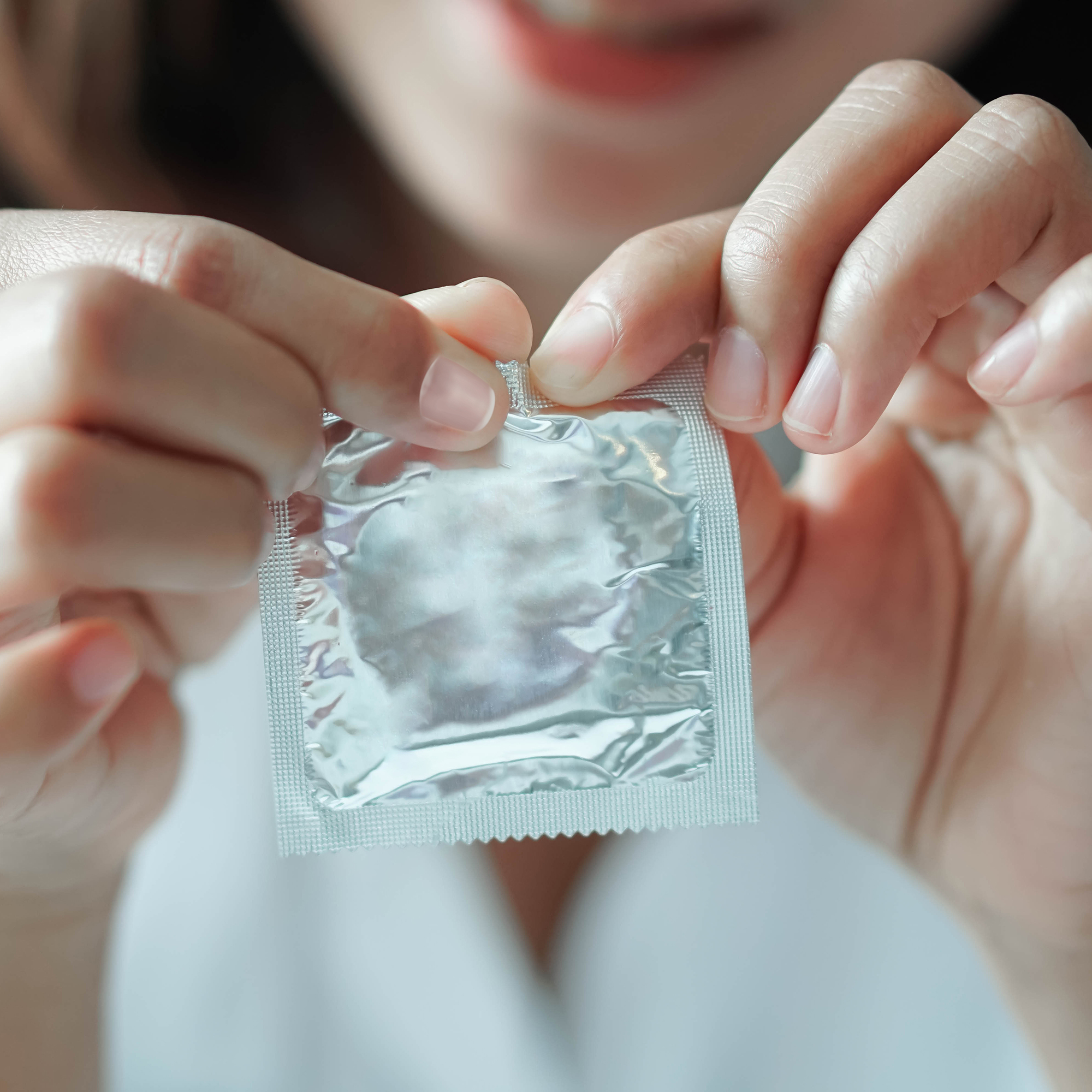 闭合女人的手打开避孕套