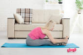 一个老女人伸展瑜伽垫。