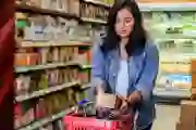 A woman reads a nutrition label in a supermarket