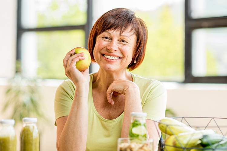 健康的女人拿着一个苹果。