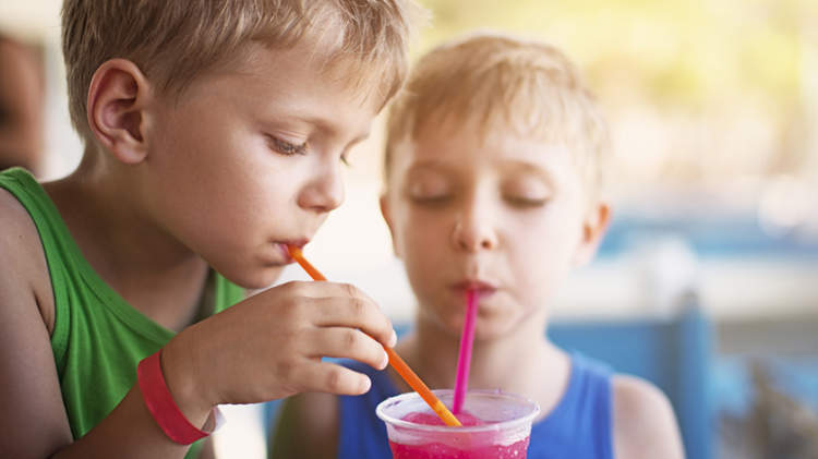 两个小男孩喝着含糖饮料和五颜六色的吸管。