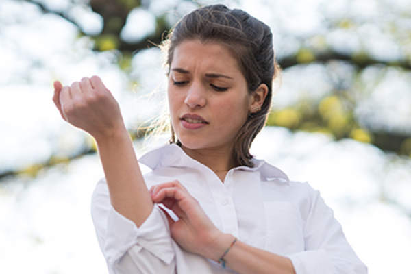 女人在户外胳臂发痒。