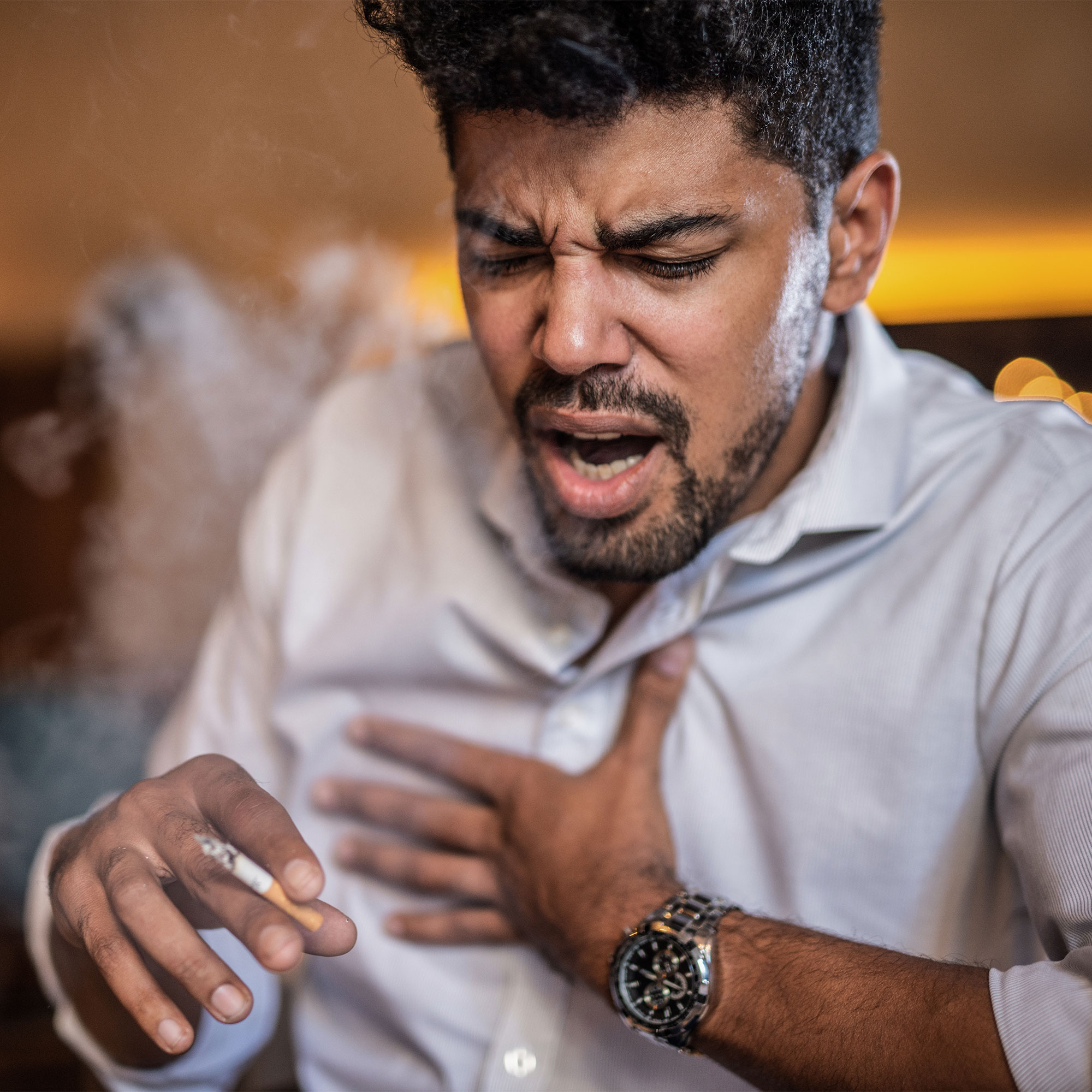 一个男人一边抽烟一边咳嗽