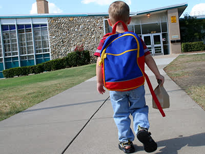 背着背包走进学校的小男孩。