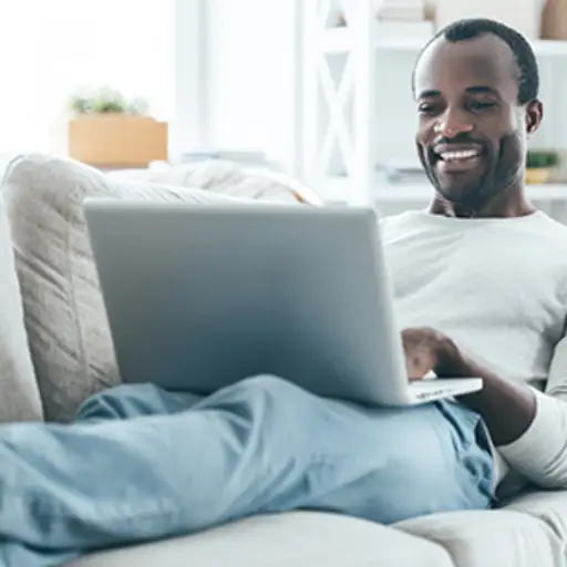 Man using a laptop at home on the couch.