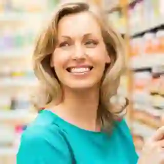 Smiling woman in supplements aisle of store.