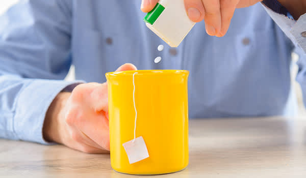 一名男子在一杯茶中添加人造甜味剂。
