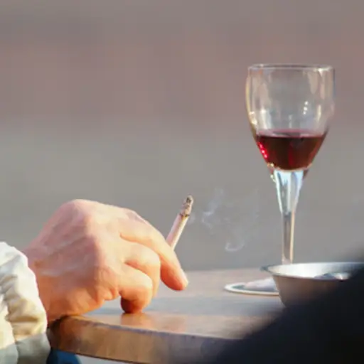 手用香烟和杯红葡萄酒。