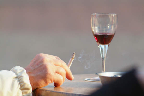 手拿香烟和一杯红酒。