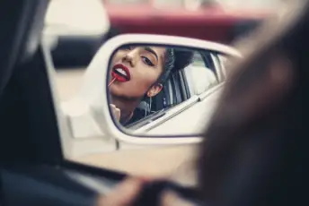 在汽车后视镜上涂口红的女人
