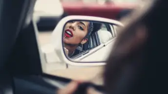 女人在汽车后视镜上涂口红