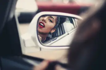 女人在汽车后视镜上涂口红