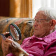 老人用放大镜看书。