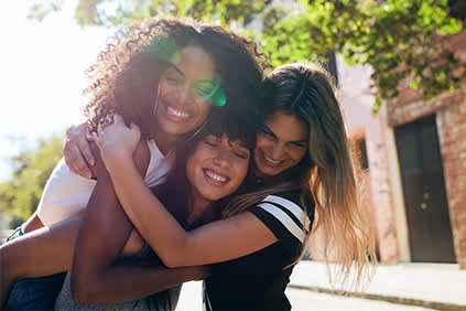 三位年轻的女性朋友，微笑和拥抱。