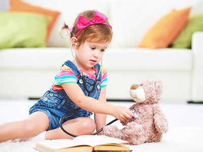 小女孩安静地玩着毛绒玩具熊。