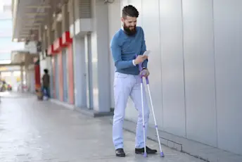 留着胡子的年轻男子拄着拐杖发短信