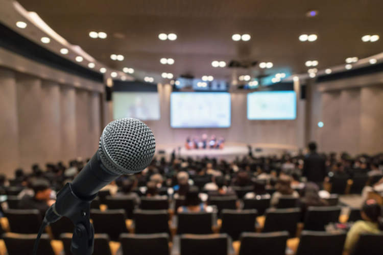 A microphone with a conference hall in the background.