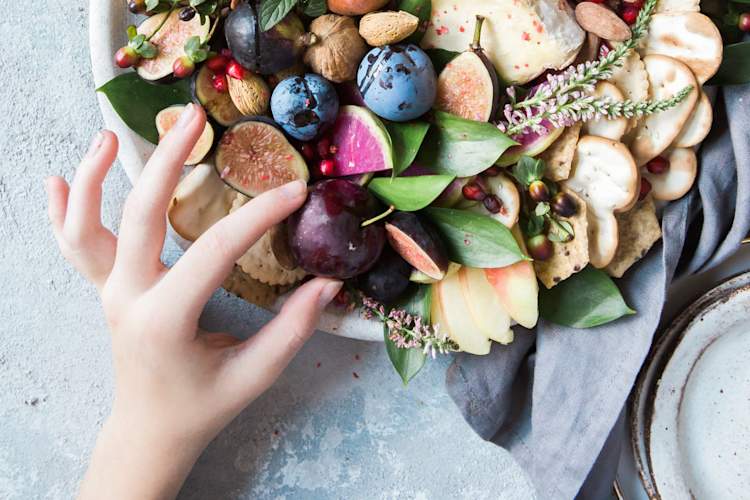 女人的手伸向盘子里的水果