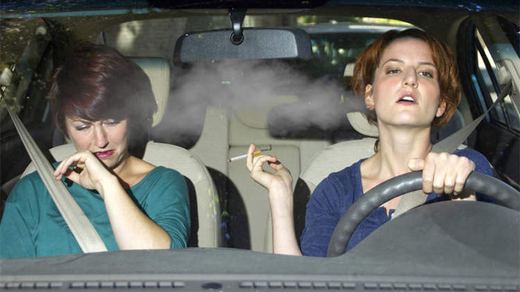 两个女人在汽车与香烟二手烟。