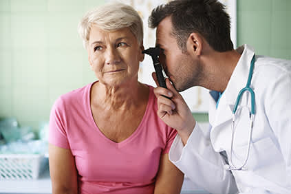 医生检查老年病人的耳朵。