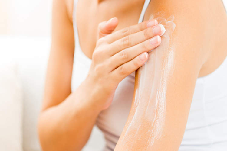 女人把乳液涂在上臂上。