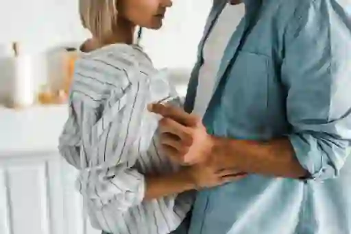 裁剪的图像的男朋友拥抱女友在厨房和避孕套