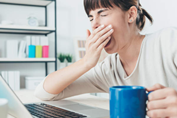 打呵欠的女人在笔记本电脑上工作