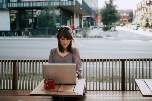 女子坐在外面的笔记本电脑工作