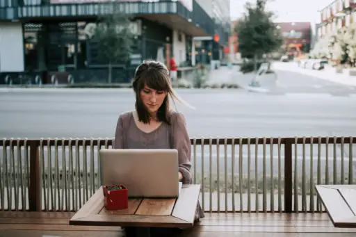 坐在外面用笔记本电脑工作的女人