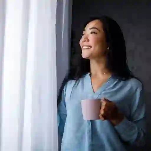 一位女士一边享受着一杯咖啡，一边透过窗户往外看