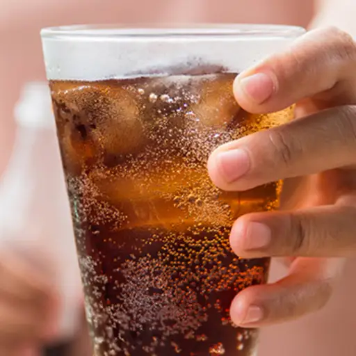 Holding a glass of soda with ice.
